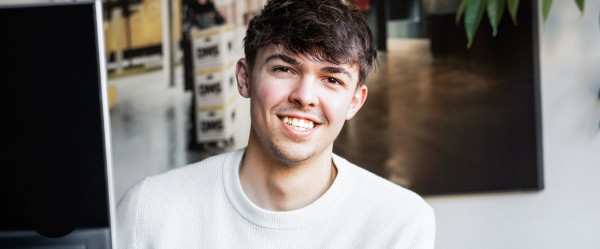 Mann der lächelnd vorm Computer sitzt.