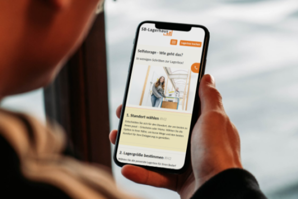 Eine Person hält ein Smartphone in der Hand, auf dem eine Website zum Thema Selfstorage angezeigt wird.