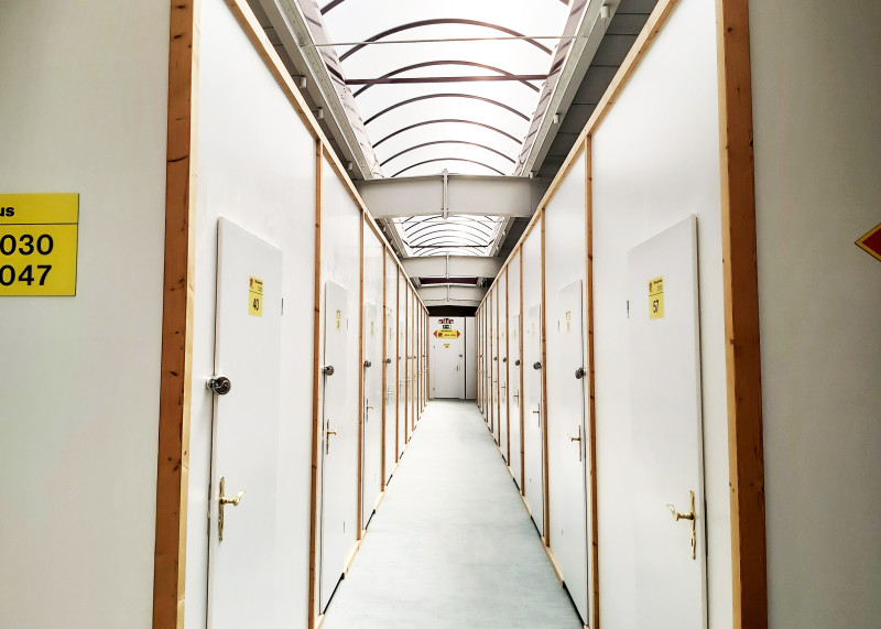 Heller Lagerflur mit weißen Türen zu einzelnen Selfstorage-Abteilen unter einem transparenten Dach.