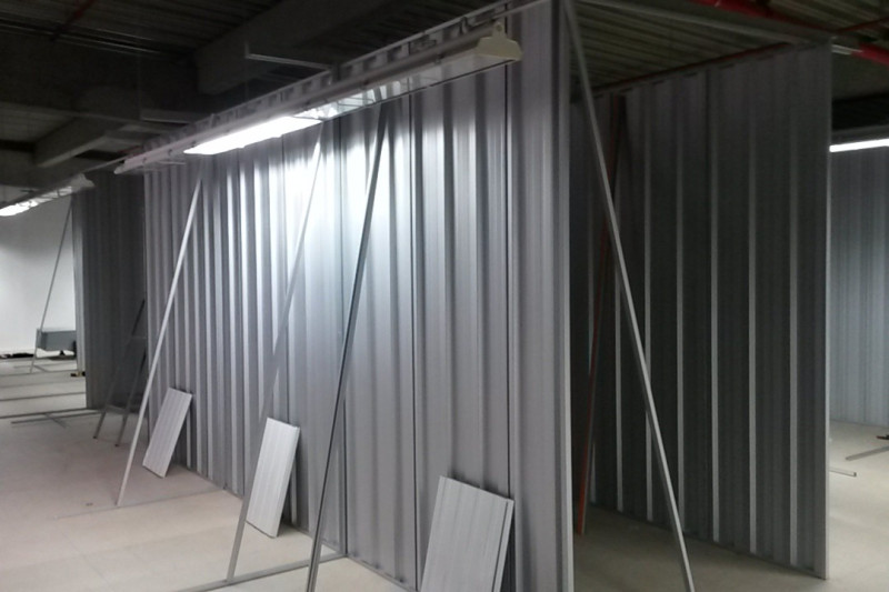 Metallene Lagertrennwände im Aufbau mit offenen Seiten und Montagegestellen in einer Industriehalle.