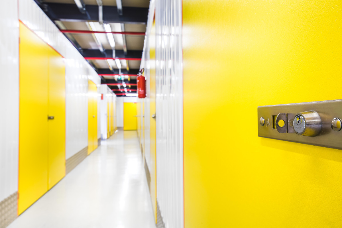 Innenansicht eines Selfstorage-Korridors mit gelben Türen und weißen Wänden.