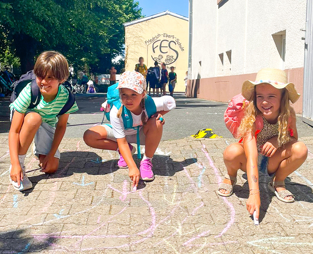 Kinder die mit Kreide auf den Boden malen.