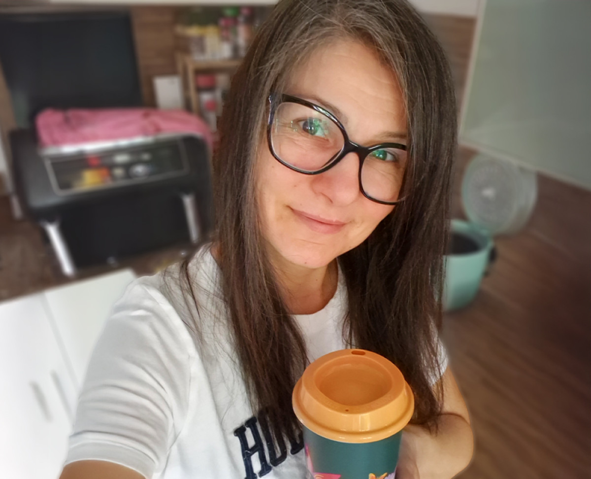 Frau mit Brille und Kaffee in der Hand.