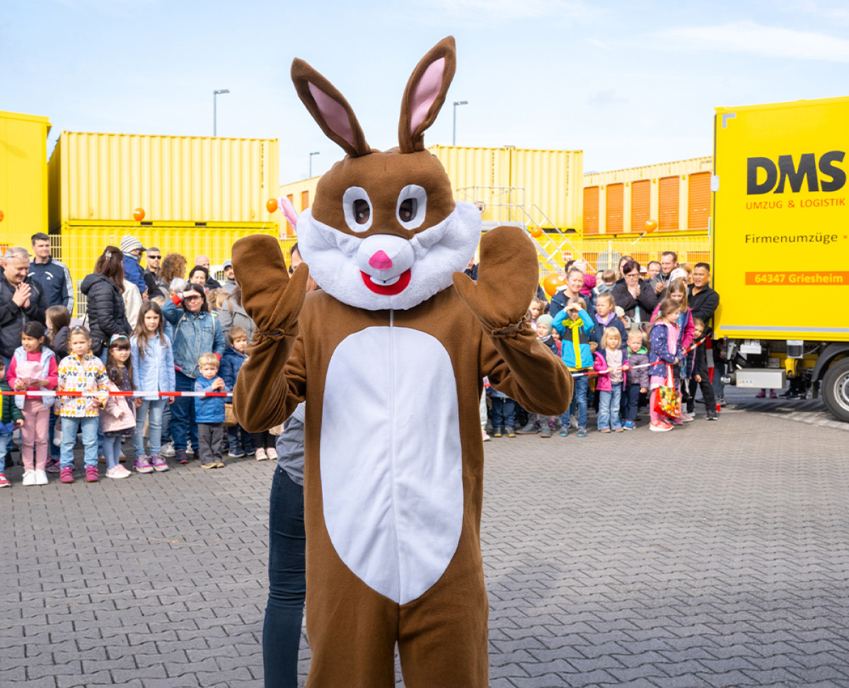 Person im Osterhasenkostüm bei einer Kinderveranstaltung im Freien, umgeben von einer Menschenmenge.