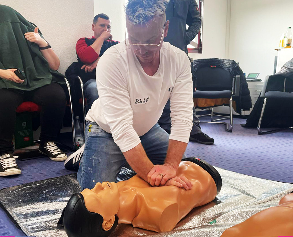 Mann übt Wiederbelebung an einer Reanimationspuppe während eines Erste-Hilfe-Kurses.