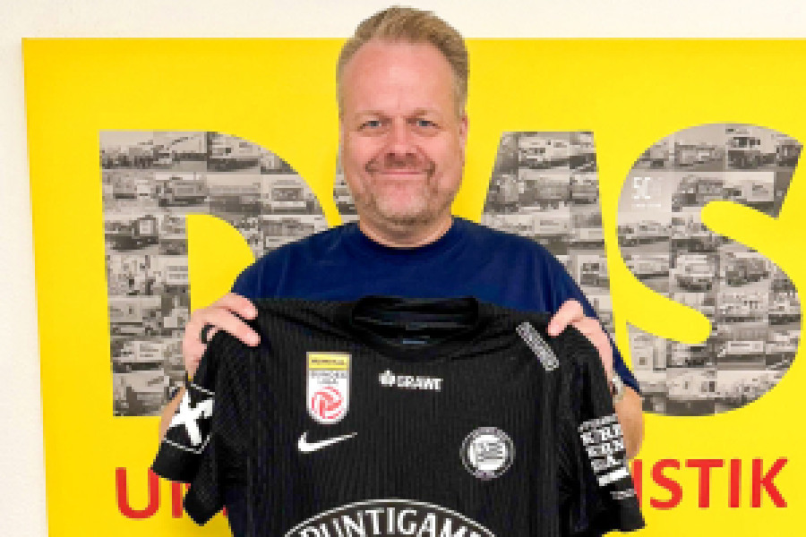 Mann hält Fußballtrikot in der Hand und lächelt