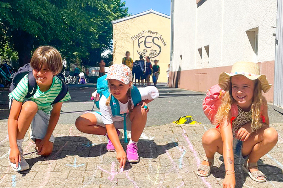 Kinder die mit Kreide auf den Boden malen.