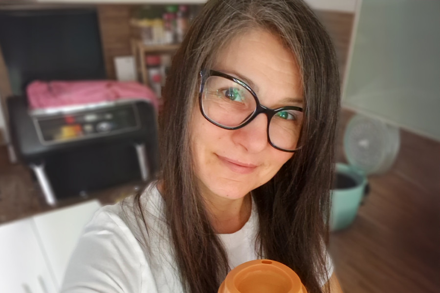 Frau mit Brille und Kaffee in der Hand.