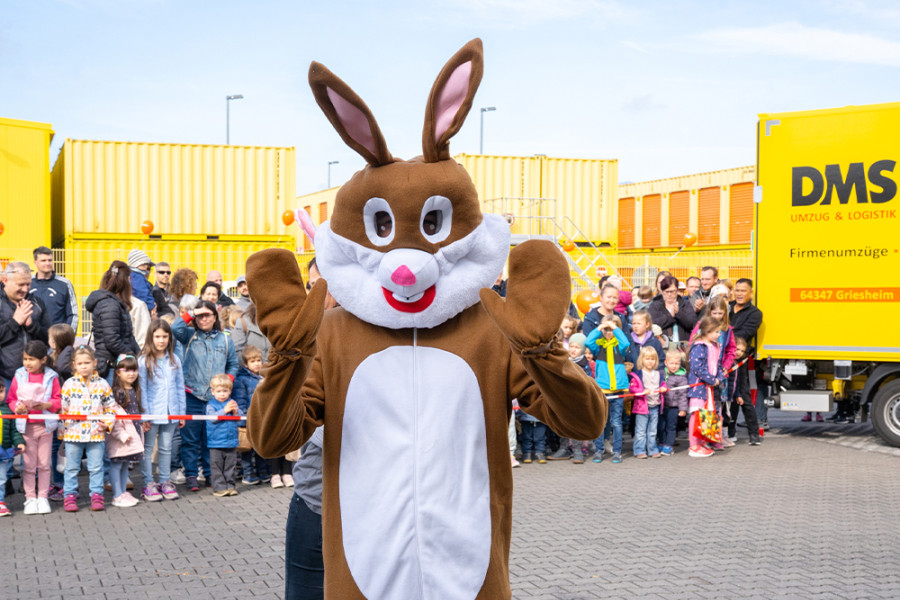 Person im Osterhasenkostüm bei einer Kinderveranstaltung im Freien, umgeben von einer Menschenmenge.